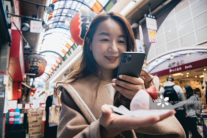 亚洲女性在日本大阪观光，在黑门市场品尝当地美食图片素材