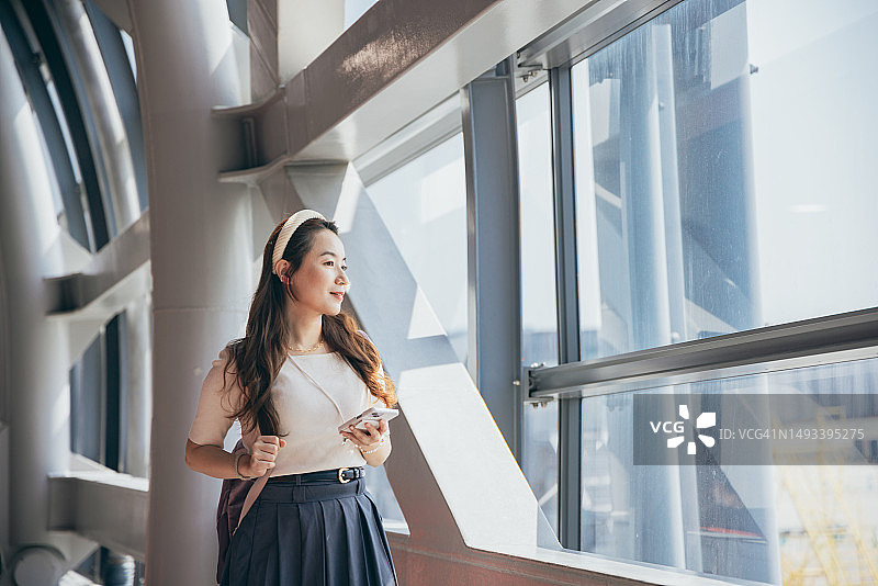 亚洲女性在机场候机厅等待，期待即将到来的旅程图片素材
