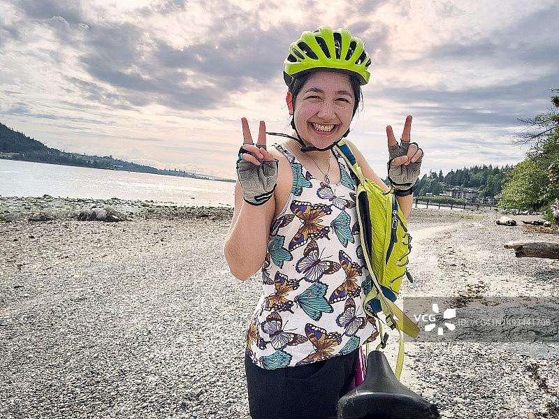 在空旷的海滩上做出和平手势的多种族年轻女骑行者图片素材