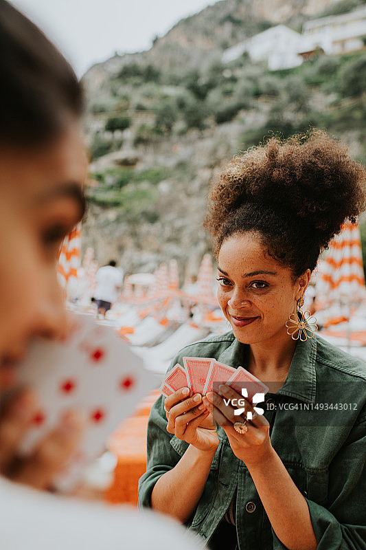 快乐的女人在海滩上玩纸牌游戏图片素材