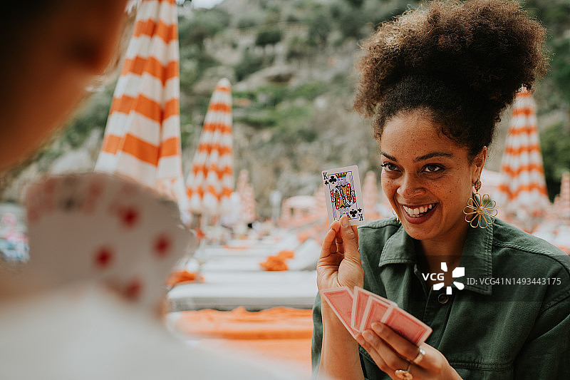 快乐的女人在海滩上玩纸牌游戏图片素材