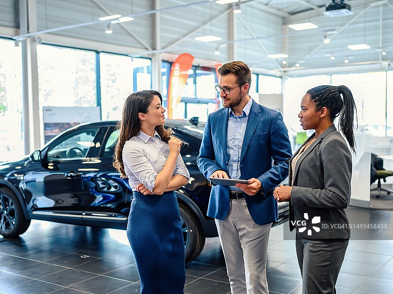 在汽车展厅里交谈的快乐商人图片素材