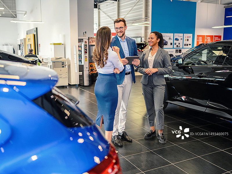 在汽车展厅里交谈的快乐商人图片素材