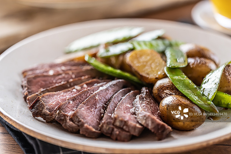 切片牛腩排配烤土豆和豌豆荚图片素材