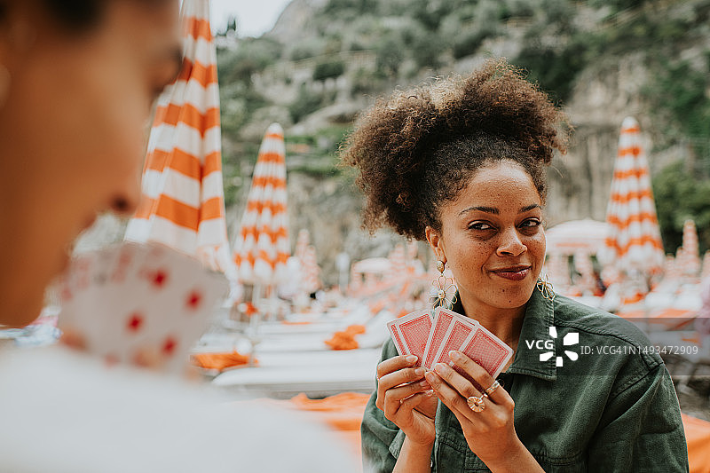 快乐的女人在海滩上玩纸牌游戏图片素材
