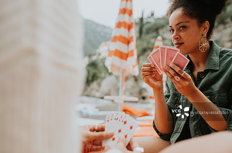 快乐的女人在海滩上玩纸牌游戏图片素材
