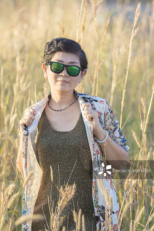 戴墨镜站在泰国草地上的漂亮亚洲女人图片素材