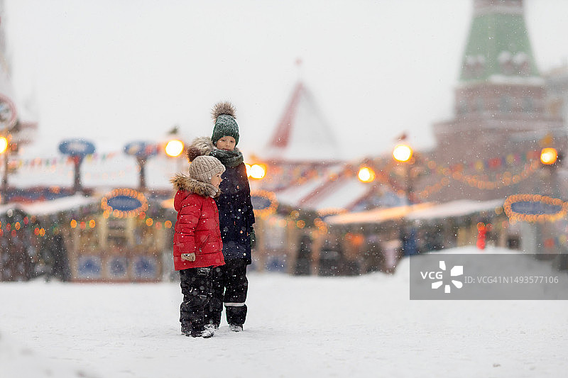 兄妹在下雪天散步。莫斯科市中心以克里姆林宫为背景的庆祝活动。图片素材