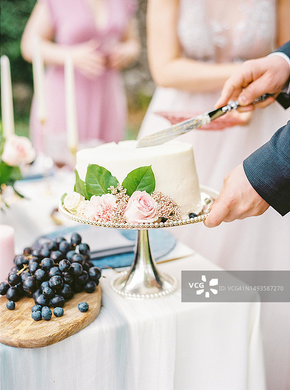 新娘在桌子上用结婚蛋糕切蛋糕的腰部特写图片素材
