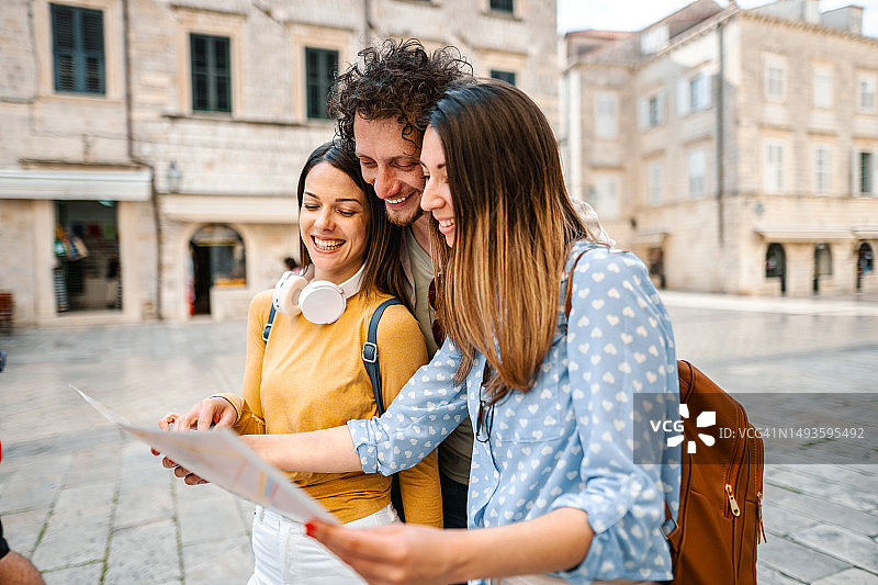三个年轻游客在探索城市时看着地图图片素材