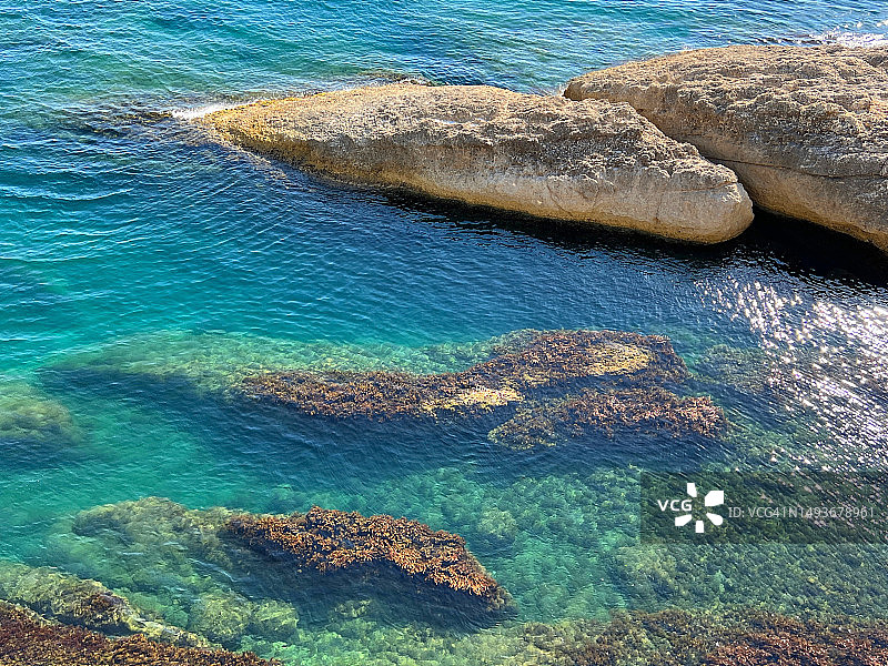地中海蓝色绿松石海水与闪光表面和海岸岩石图片素材