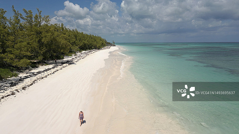 航拍：女子漫步在空旷的沙滩上图片素材