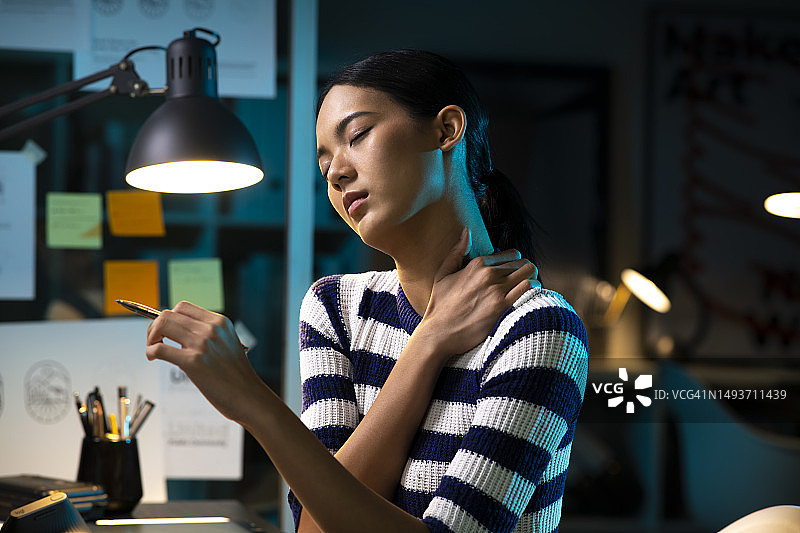 亚洲女平面设计师在晚上工作时颈肩疼痛图片素材