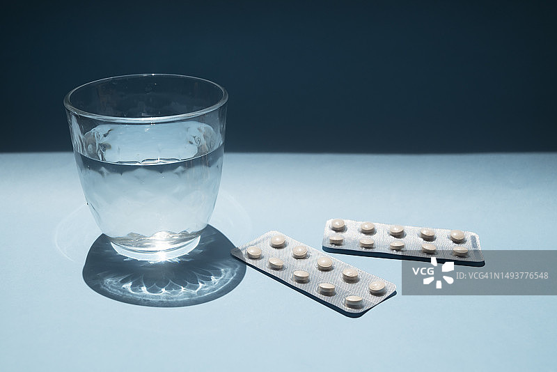 蓝色背景上装有药丸的水杯图片素材