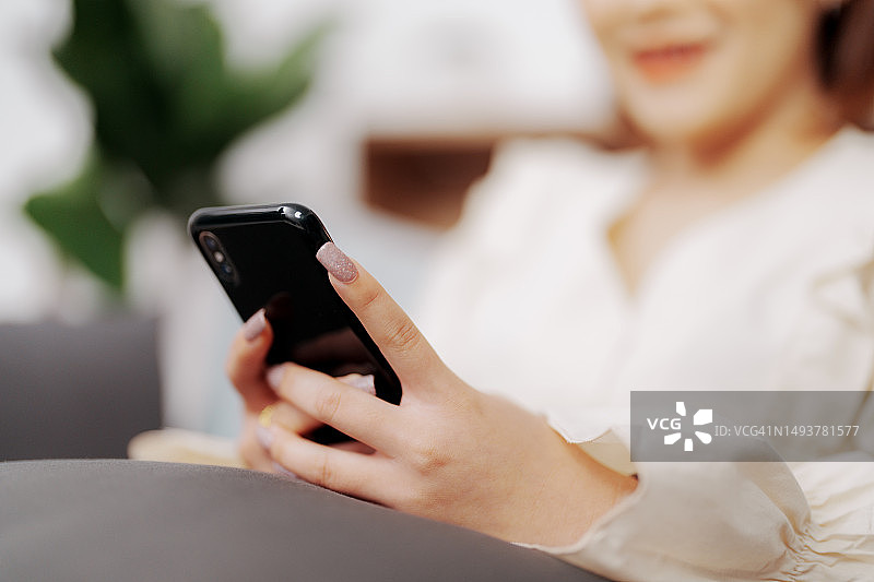 女人们坐在客厅的沙发上玩手机游戏图片素材