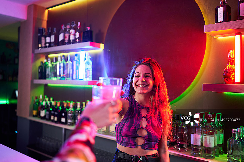 在迪斯科舞厅里，调酒师和无法辨认的顾客祝酒图片素材