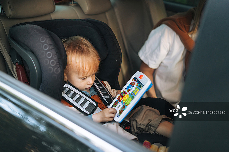 男婴坐在车里，系好安全带，和妈妈一起玩音乐玩具图片素材