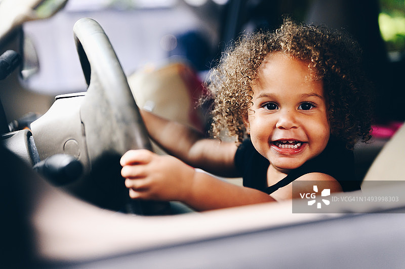 可爱快乐的混血宝宝假装开家里的车图片素材