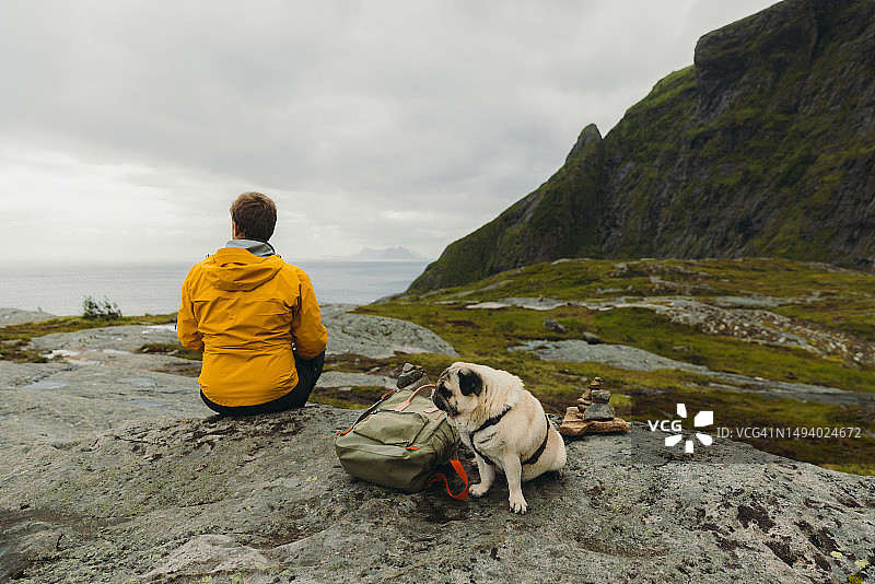 男子和狗在罗弗敦群岛户外思考夏日图片素材
