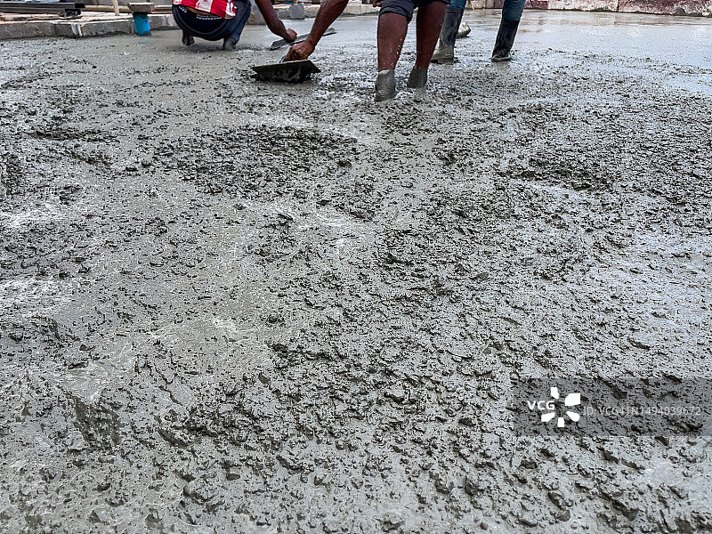 许多建筑工人浇筑水泥抹平地面。图片素材