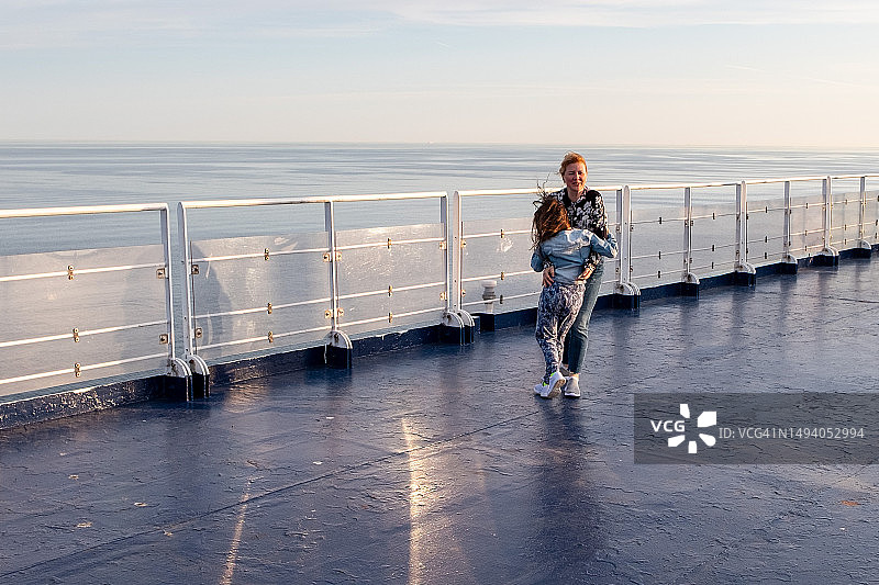 7岁女孩与年轻女子在游轮甲板上拥抱，背景为波罗的海图片素材