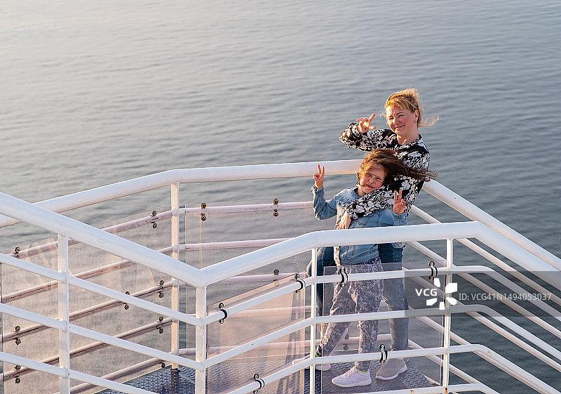 一家人站在甲板上对着相机微笑，海上邮轮之旅图片素材