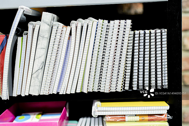文具店里排列在架子上的螺旋笔记本图片素材