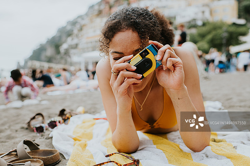 年轻女子在海滩上用一次性相机拍照图片素材