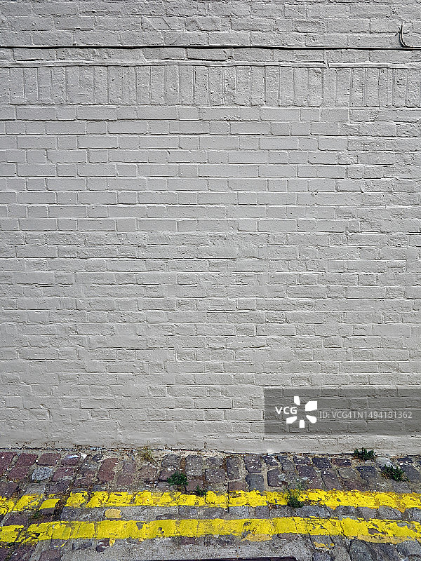 伦敦的白色砖墙、电缆和黄色禁停线街道图片素材