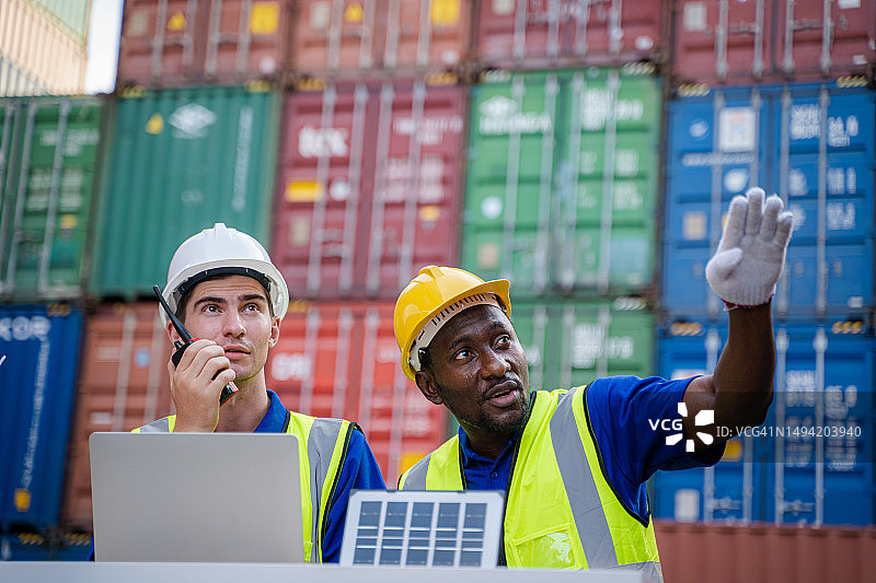 货物运输进出口行业，工人在海外集装箱堆场与同事合作图片素材