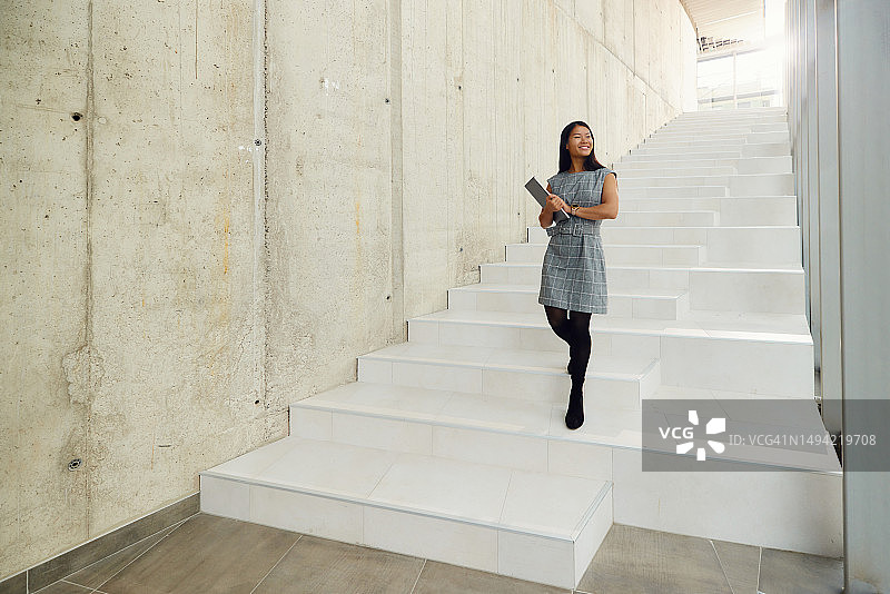 快乐的亚洲女商人走下走廊的楼梯图片素材