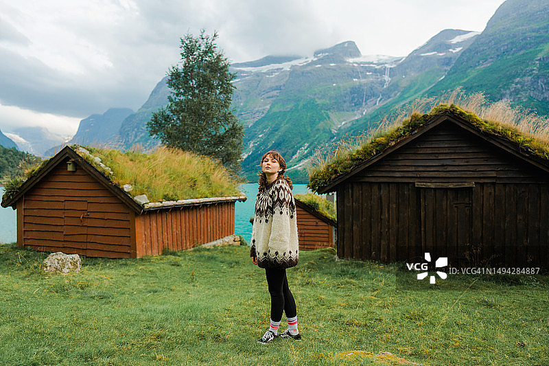 站在峡湾背景的苔藓小屋附近的女人图片素材