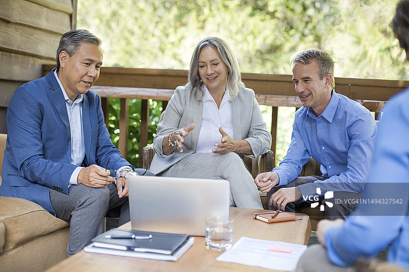 成熟的资深商业同事在公司务虚会的会议上与同事合作并讨论笔记本电脑的想法图片素材