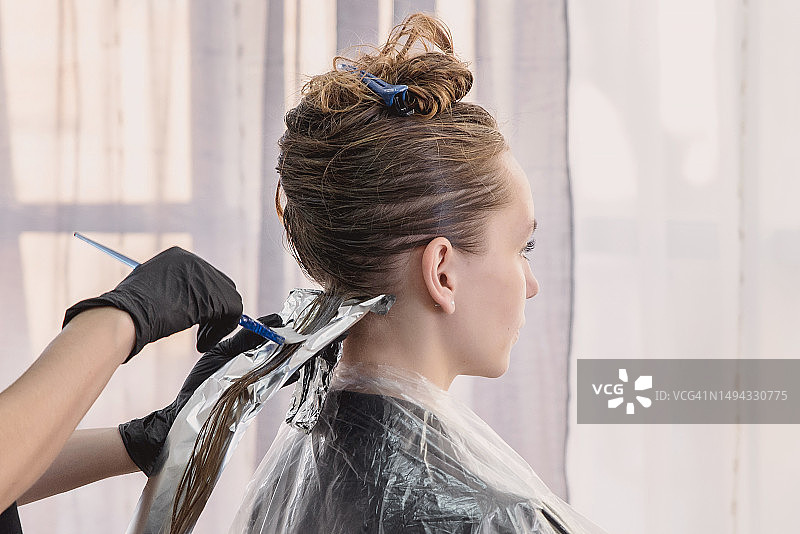 发型师用锡纸为年轻女子染发图片素材