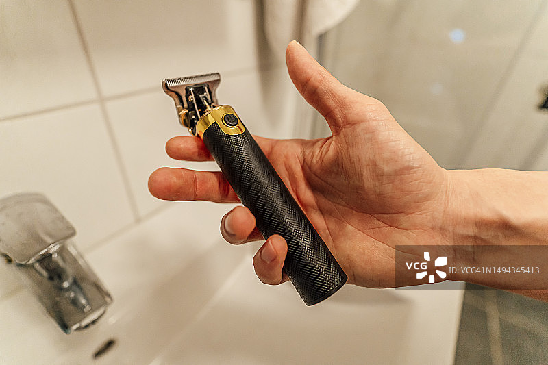 男人在浴室里拿着电动剃须刀图片素材