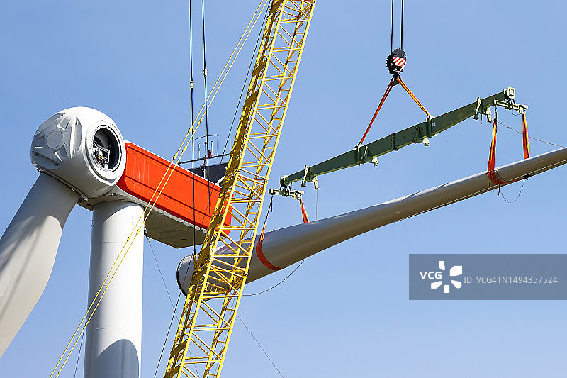 风力涡轮机建筑工地 - 起重机将转子叶片吊到发电机上图片素材