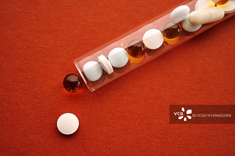 橙色背景试管中的药片、维生素和膳食补充剂图片素材