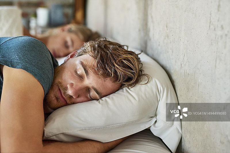 年轻男人在床上睡在女人旁边图片素材