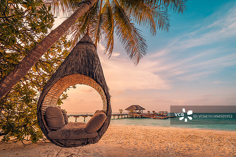 最佳梦幻海滩假期。多云天空下的美丽热带马尔代夫海滩。爱之秋千吊床悬挂在椰子树上。奢华度假概念，宁静的海岸。迷人的日落度假景观图片素材
