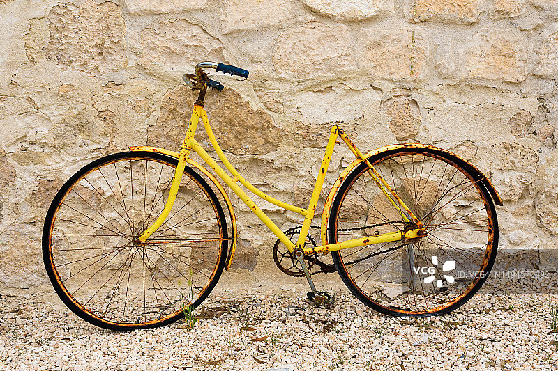 石头墙边的锈迹斑斑的黄色自行车，约克半岛，南澳大利亚图片素材