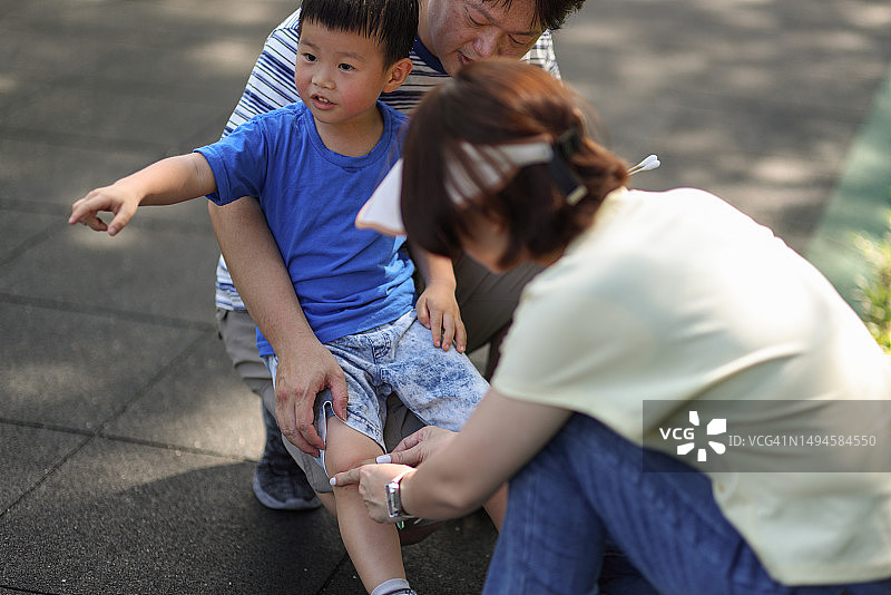 父母在公园里为受伤的孩子包扎伤口图片素材