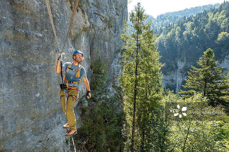 在铁索栈道上通过猴桥的运动型男人图片素材