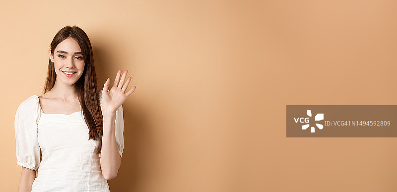 友好的微笑的女人说你好，挥手向你打招呼，站立图片素材