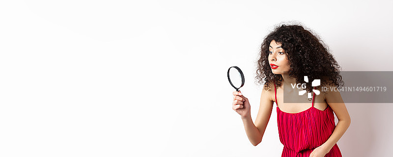 穿着红色连衣裙的漂亮女人正在寻找东西图片素材