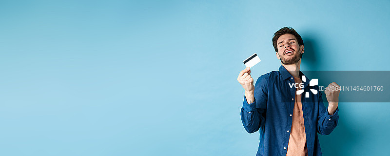 快乐的年轻人拿着信用卡跳舞图片素材