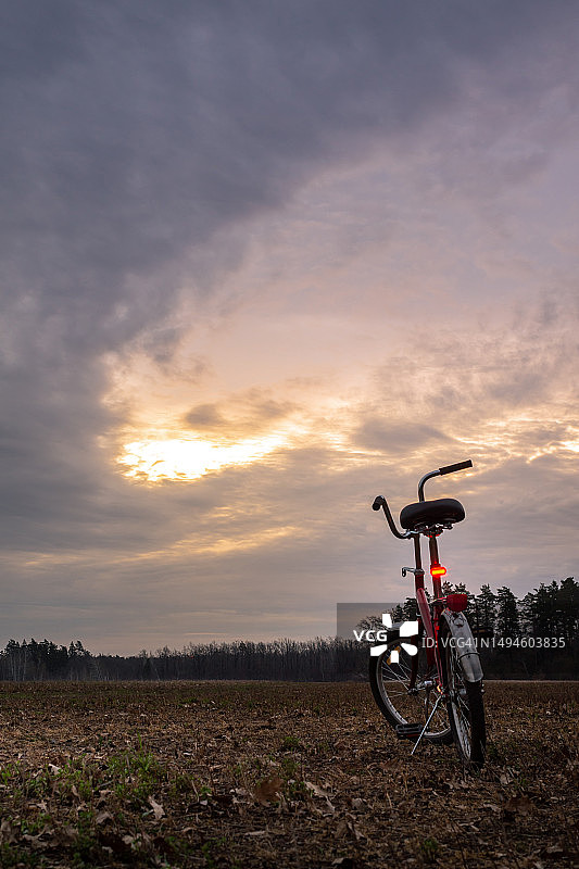 日落时分，男子骑自行车站在田野上图片素材