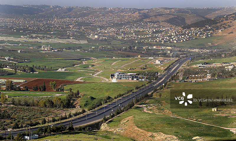 一条长长的街道和旁边的农田，位于约旦安曼北部图片素材