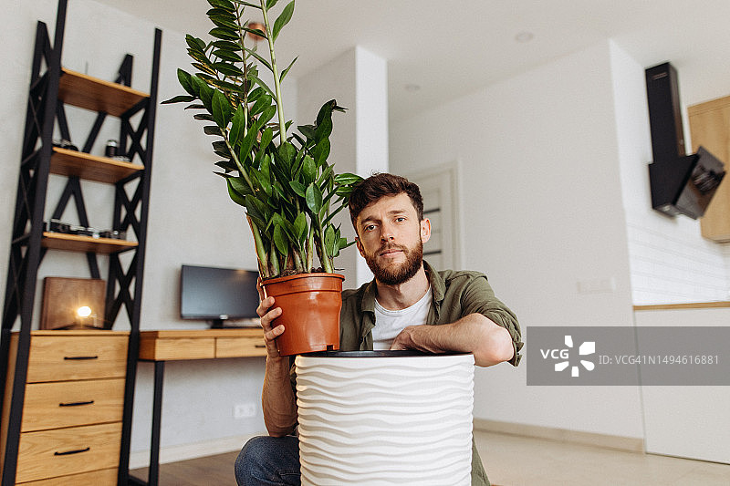 男子满意地抱着家里的盆栽准备种植图片素材