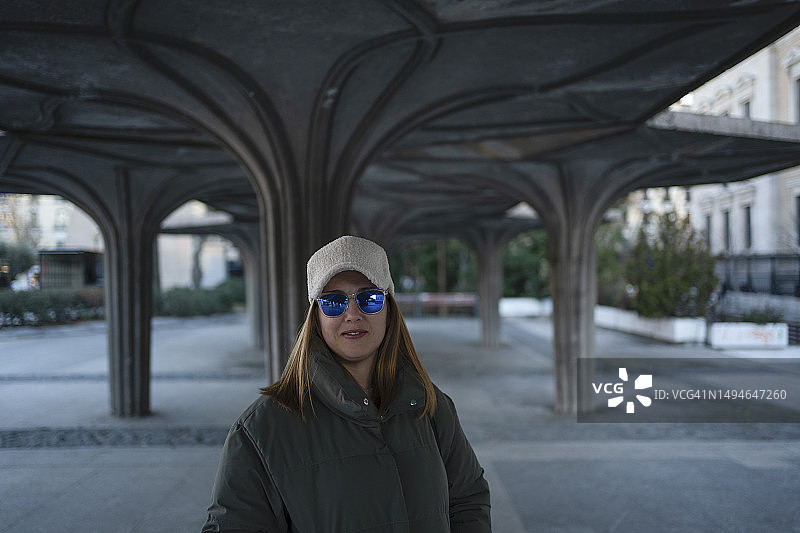 在马德里街头穿着冬季外套、戴太阳镜和运动帽的女士 портрет图片素材