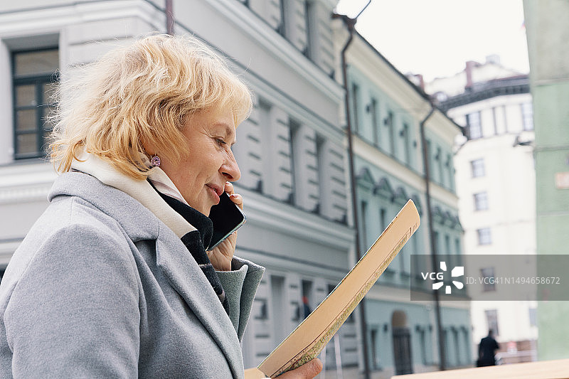 在商务旅行中，用手机通话并使用地图在城市中导航的商务女性图片素材